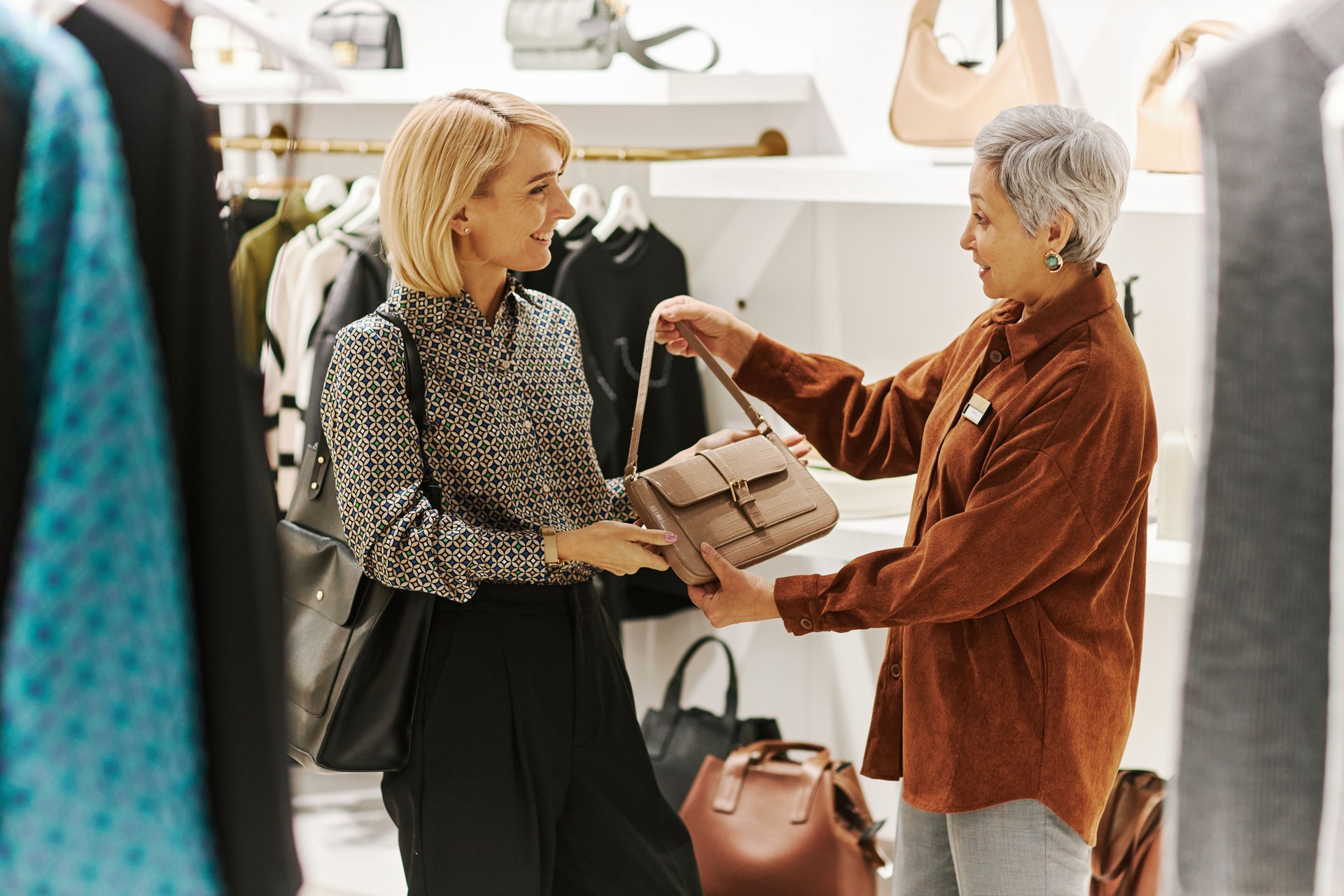 Adult mother and daughter enjoying shopping together and choosing bags boutique